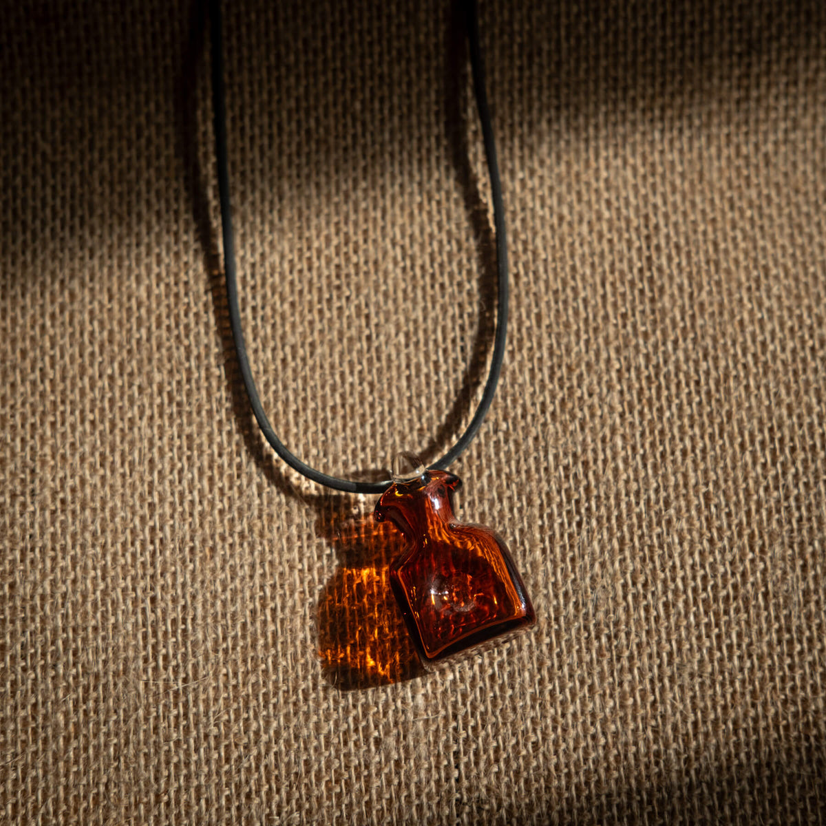 Necklace with a small amber-colored pendant on a textured brown background