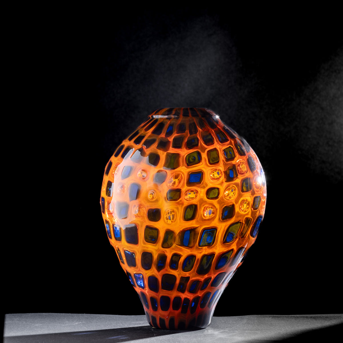 Colorful glass vase with geometric pattern on a black background