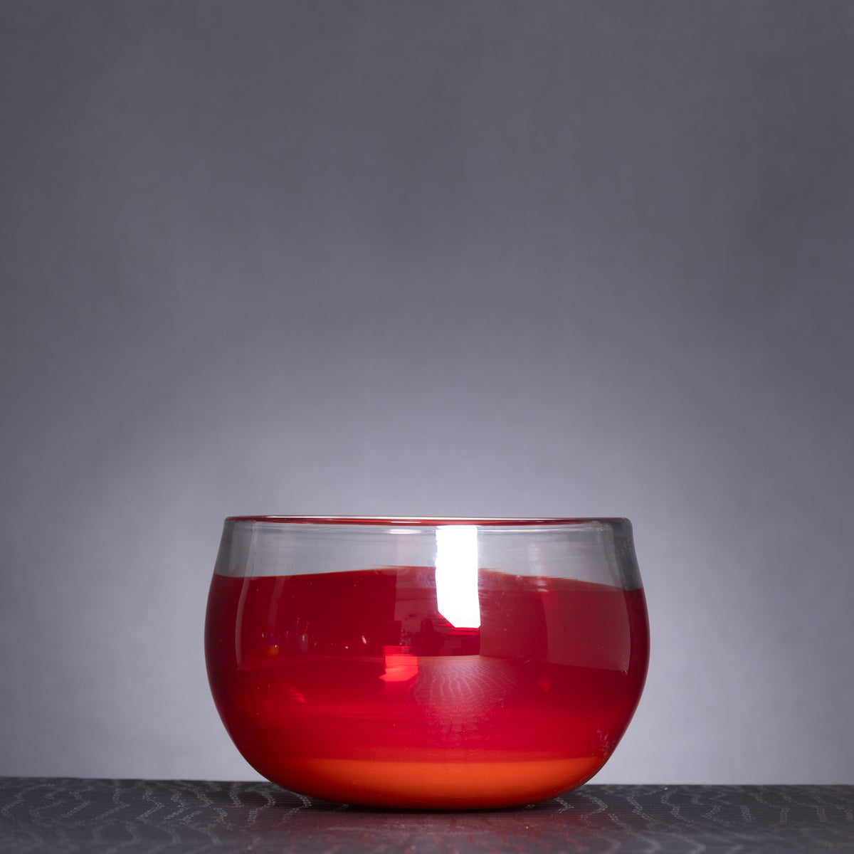 Clear glass bowl with red liquid on a gray background