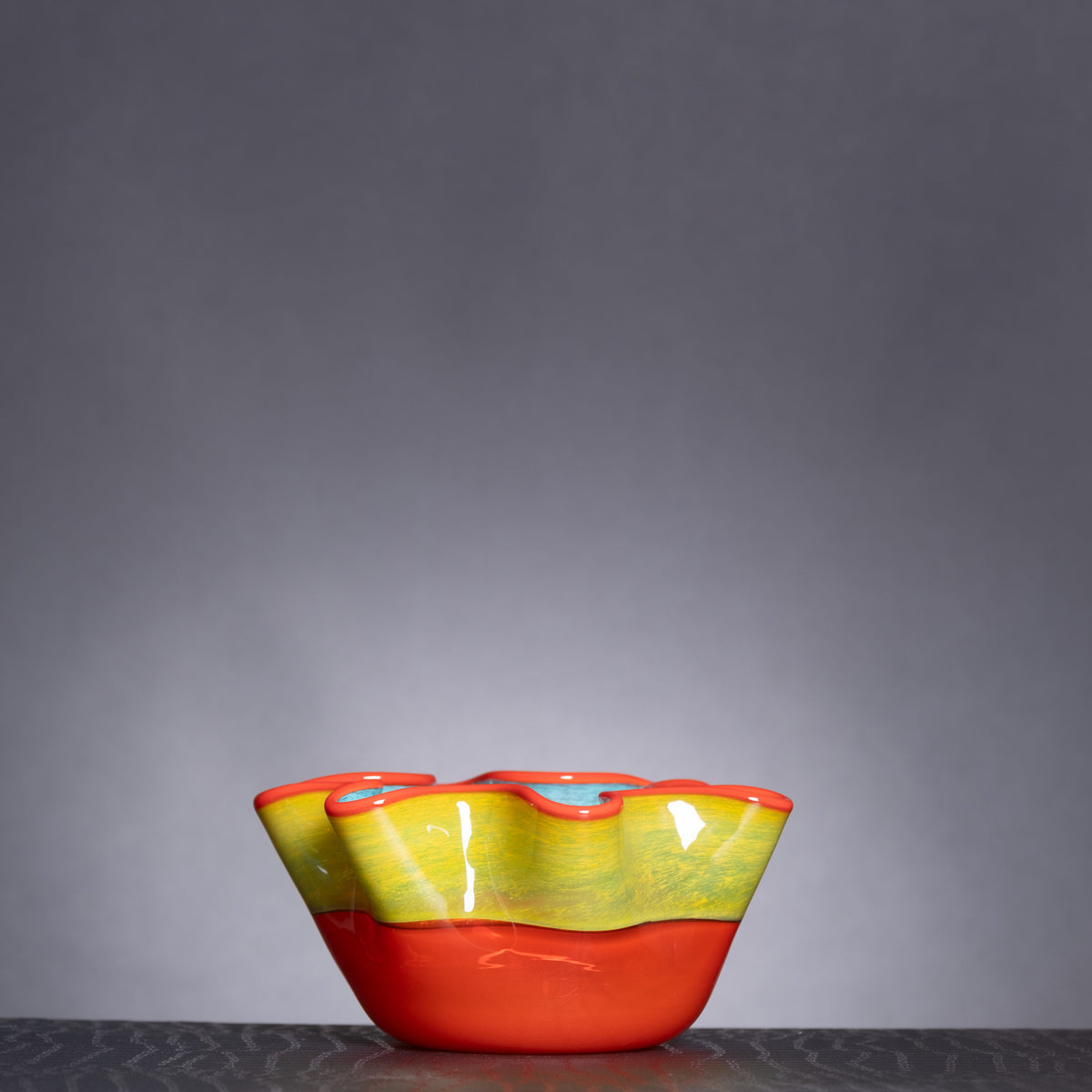 Colorful ceramic bowl with red and yellow design on a gray background