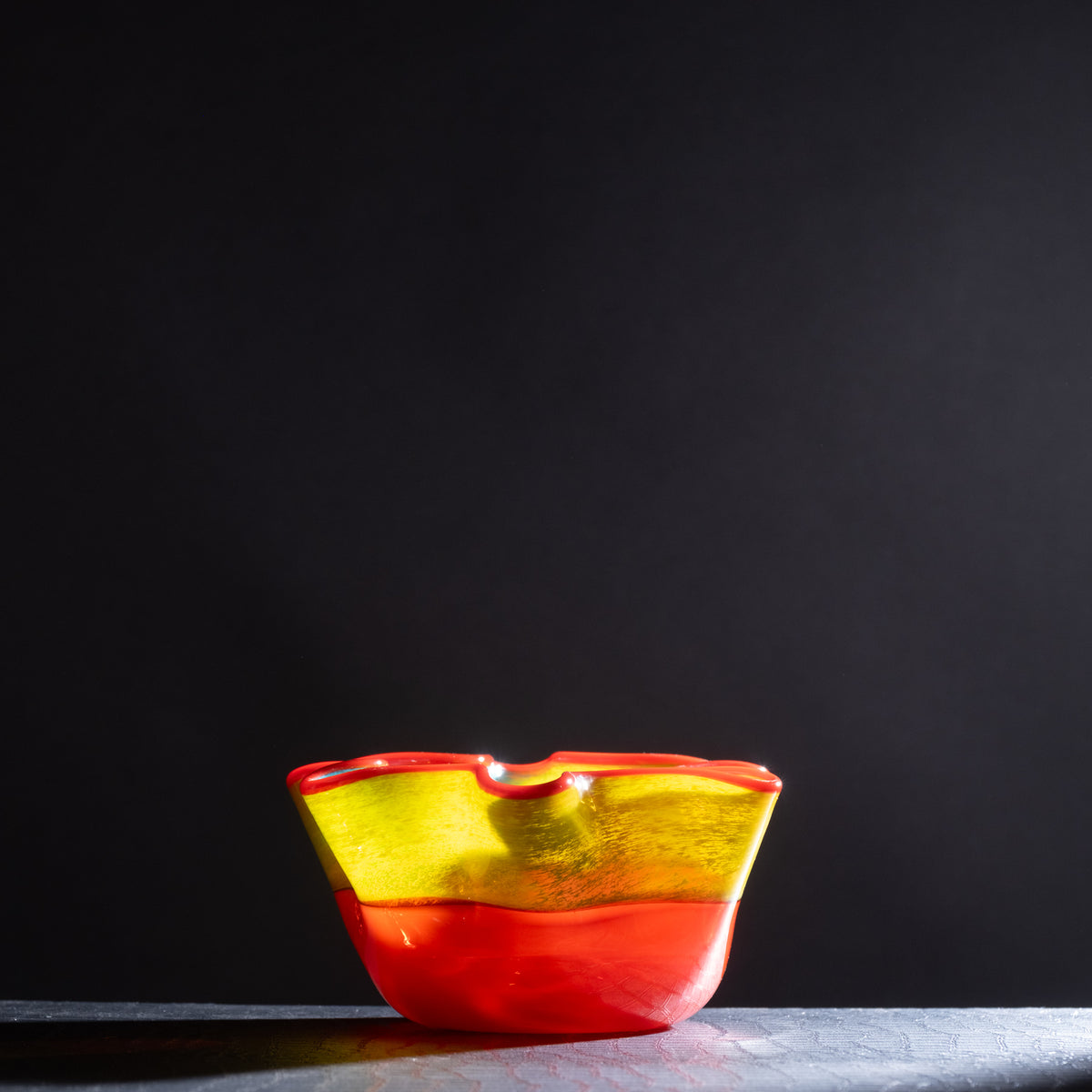 Glass bowl with red and yellow gradient on a dark background
