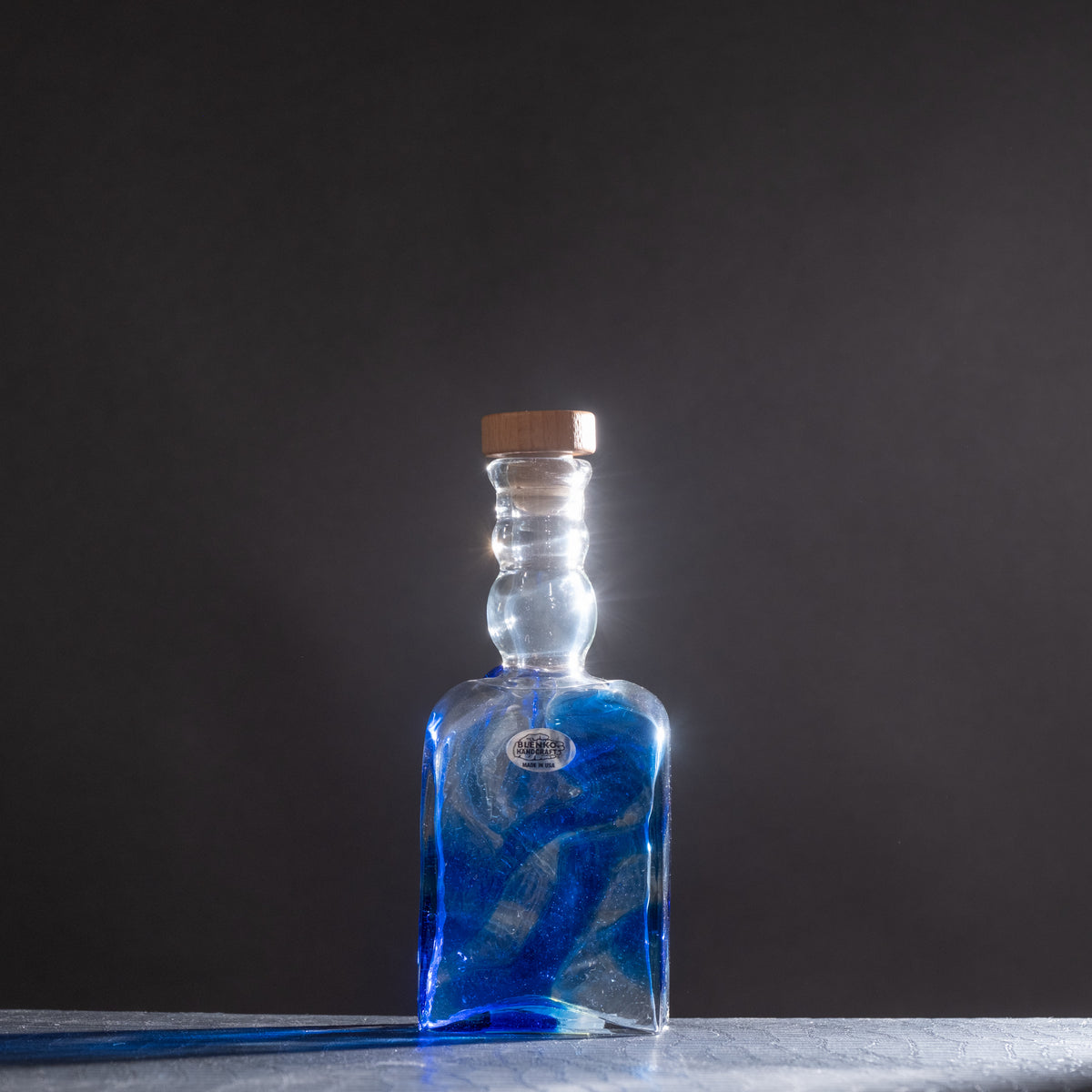 Blue glass bottle with cork on a dark background