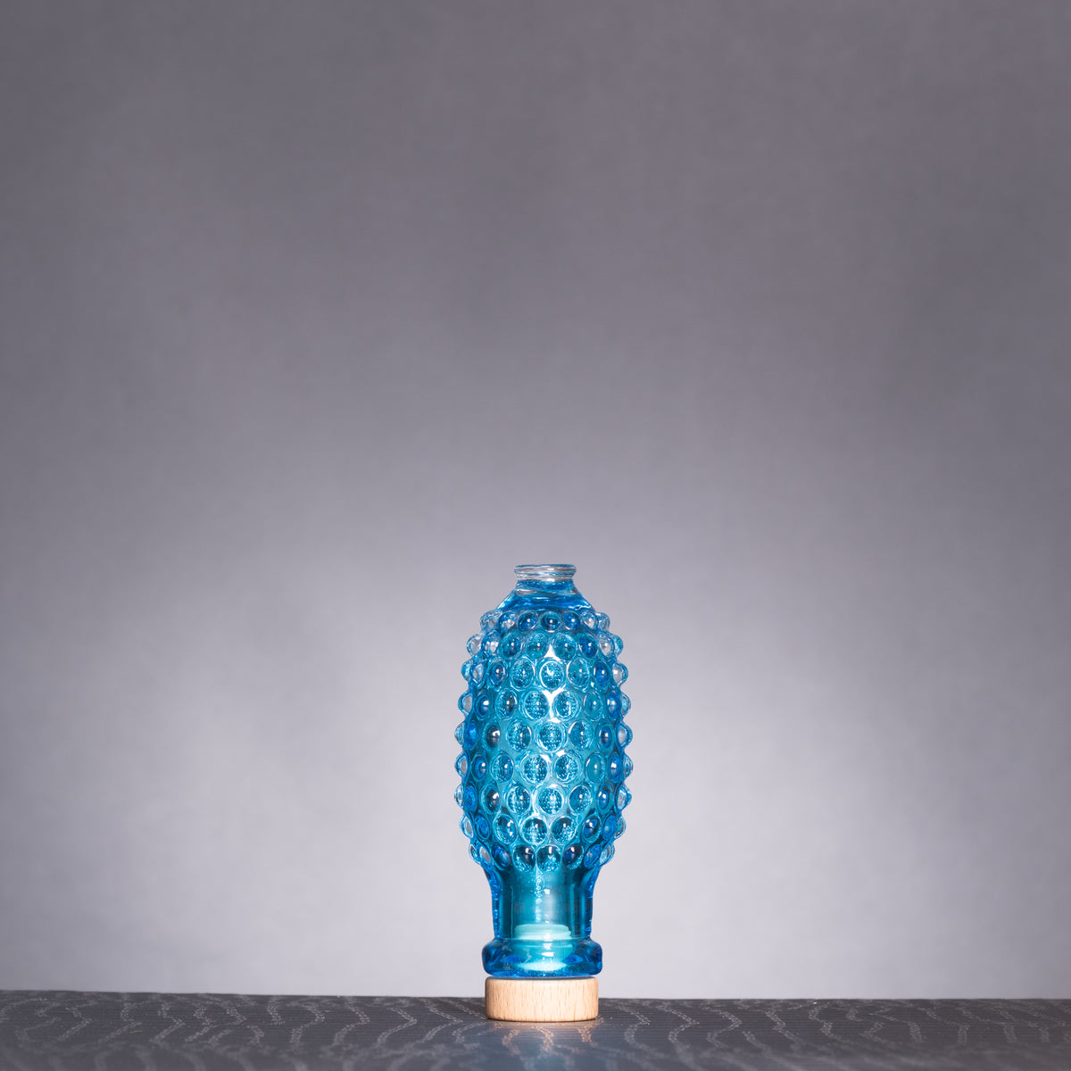 Blue textured vase on a gray surface with a gray background