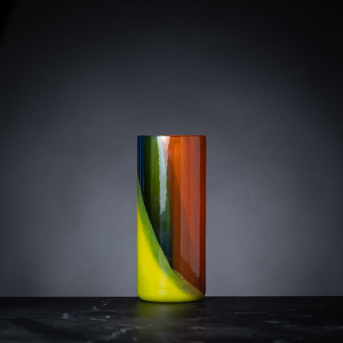 Colorful glass vase on a dark surface with a gray background
