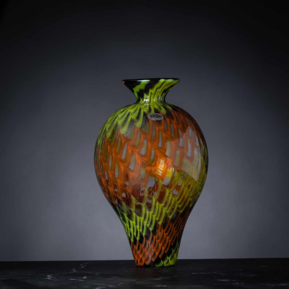 Colorful glass vase with intricate patterns on a dark background