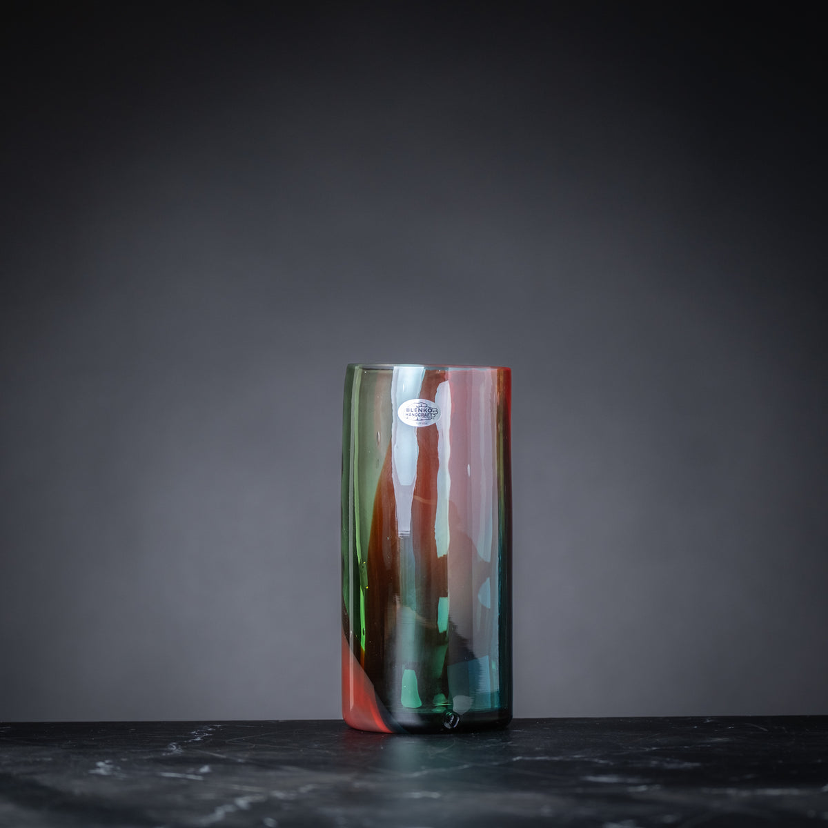 Multicolored glass vase on a dark surface with a gray background