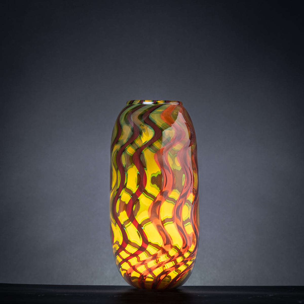 Colorful glass vase with wavy pattern on a dark background