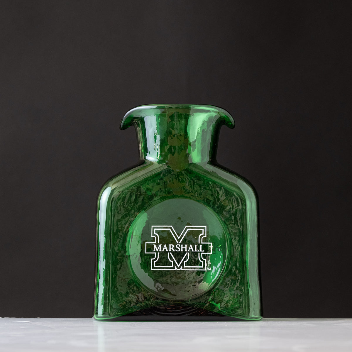 Green glass vase with Marshall University logo on a dark background