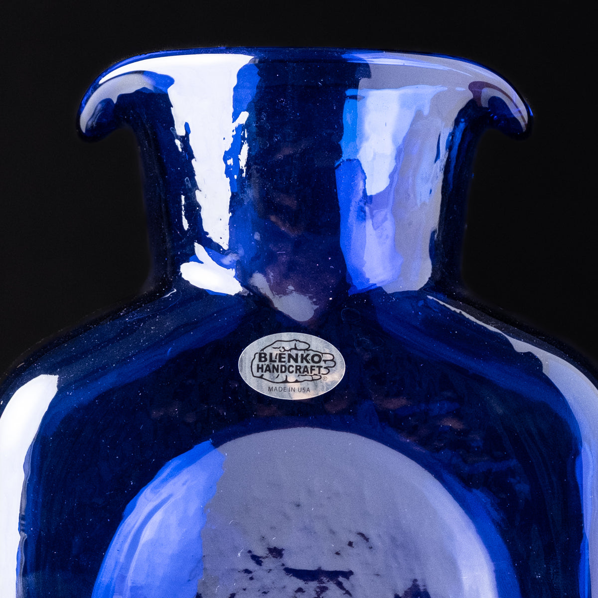 Blue glass vase with 'Blenko Handcrafts' label on a black background