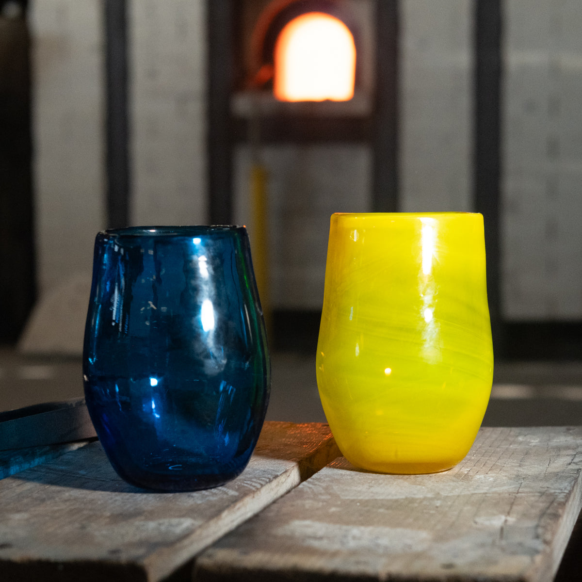 Blue and yellow glass tumblers on a wooden surface with a blurred background