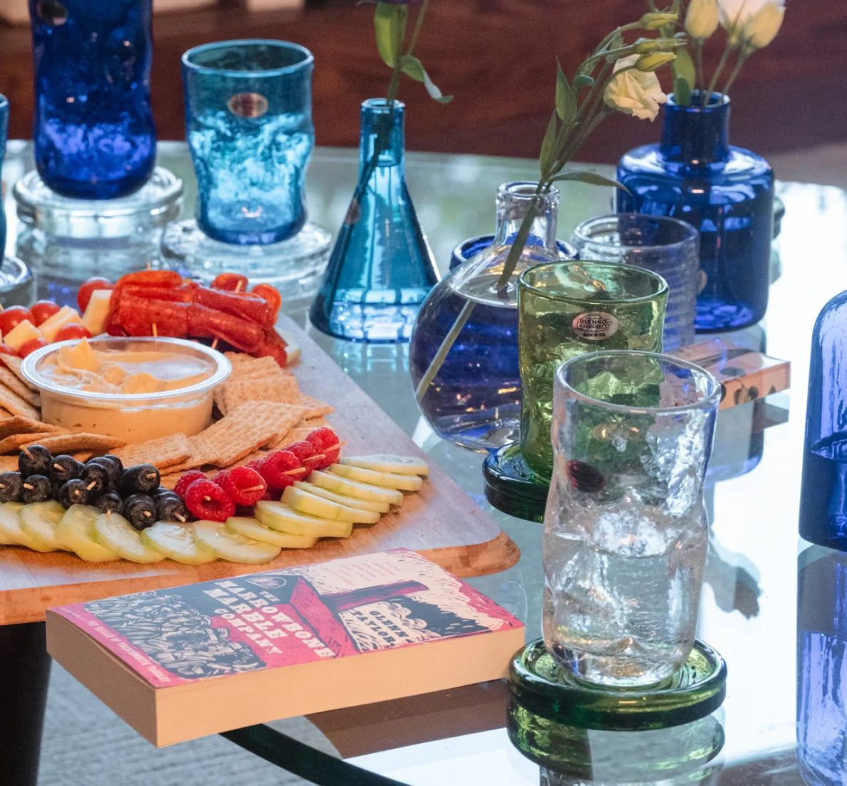 Charcuterie board with food on it surrounded by glass.